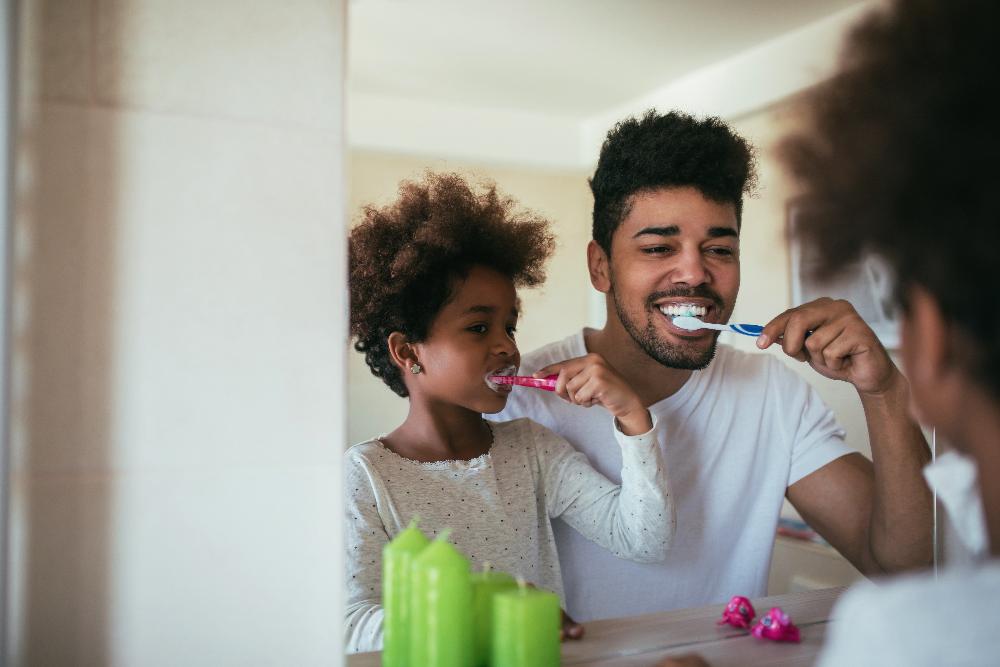 father and daughter brushing their teeth 