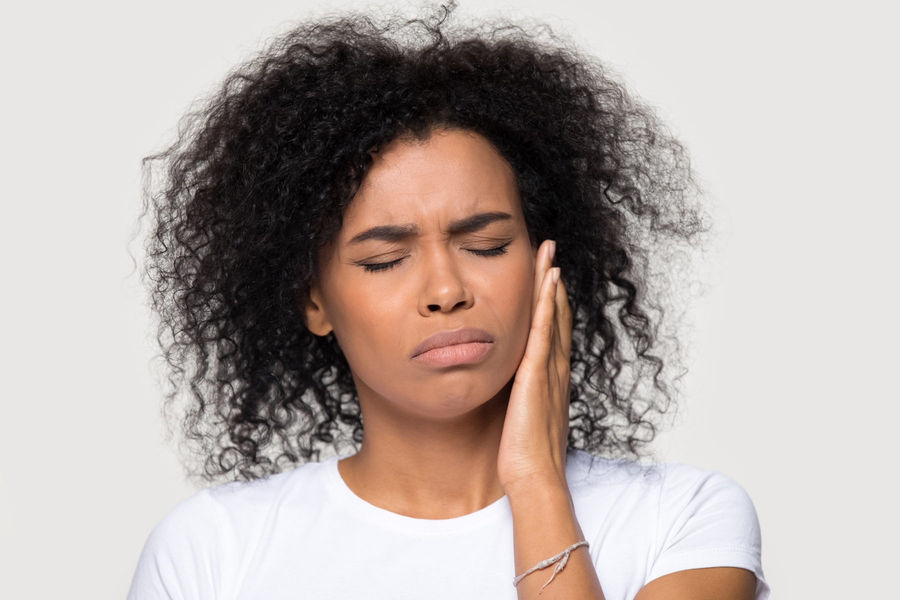 woman holding jaw in pain from TMJ disorder