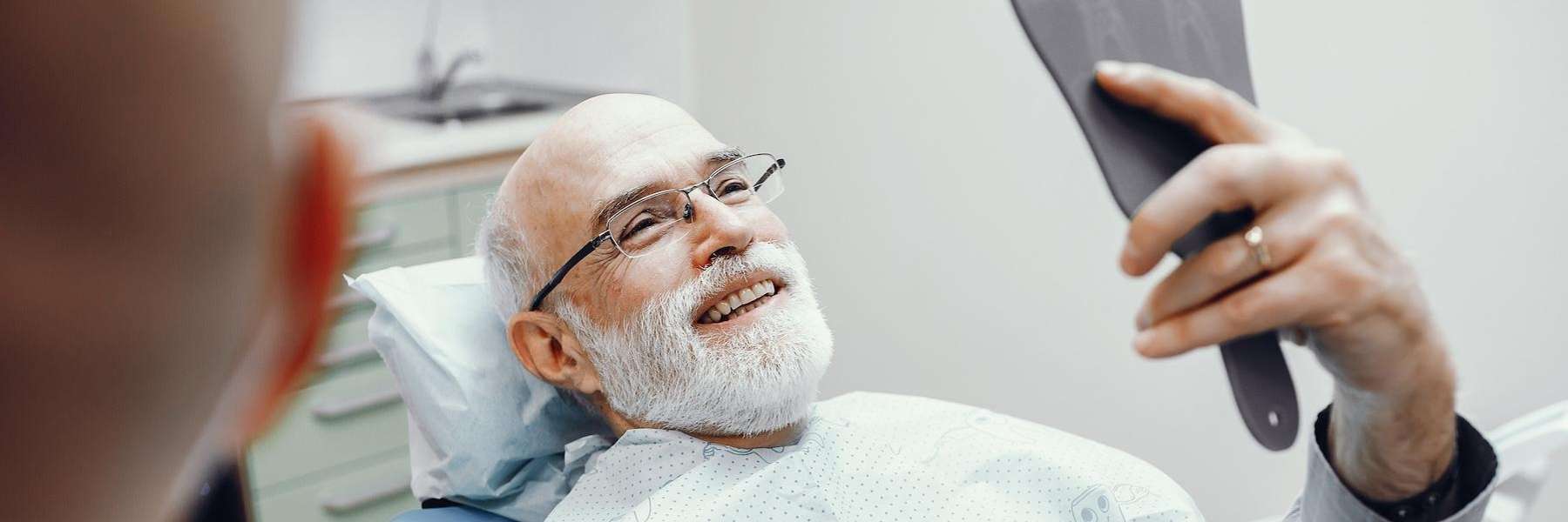 older man admiring his smile at the dentist in brentwood